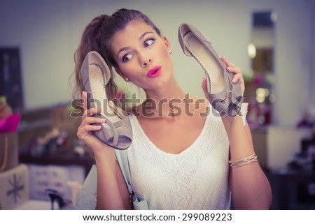 Woman holding high-heeled sandals and having fun at a shoe shop