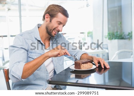 Young happy man eating his cake in the cafe