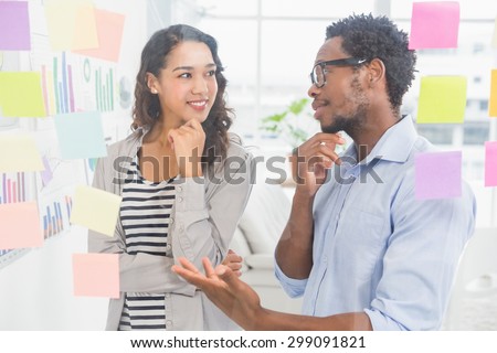 Young creative business people at the office talking to each other with sticky notes at the wall