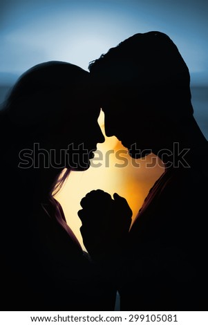 sunset of a beautiful day against silhouette of affectionate couple face to face holding hands