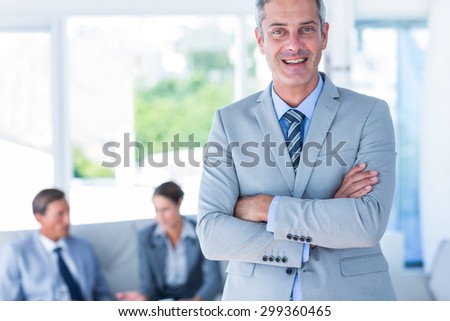 Businessman looking at camera with his colleagues behind him in office