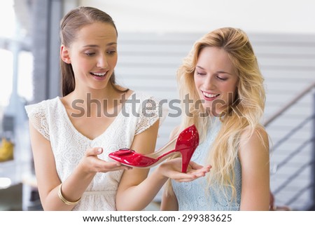 Happy women looking at a heel shoe in shoe store