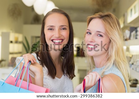 Happy women friends smiling at camera with shopping bags in a beauty salon
