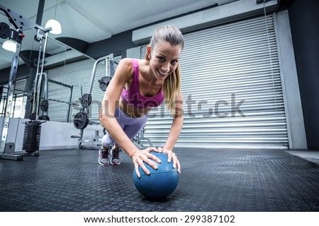 Muscular woman on a plank position with a balance ball