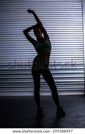 Portrait of a muscular woman stretching in shadow room