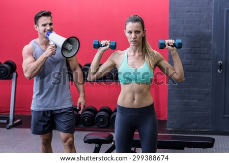 Trainer yelling through the megaphone while woman lifting dumbbells