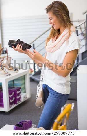 Smiling woman holding laced shoe at a shoe shop