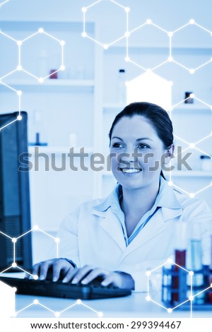 Science graphic against smiling scientist typing a report with her computer