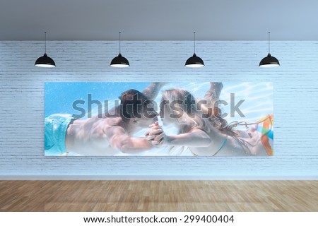 Cute couple kissing underwater in the swimming pool against room with poster display