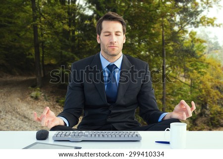 Calm businessman sitting in lotus pose against tarmac curved country road in forest