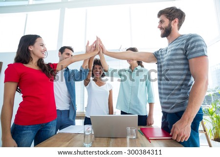 Happy business team putting their hands together in the office