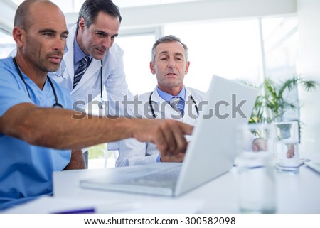 Doctor showing laptop pc to his colleagues in medical office