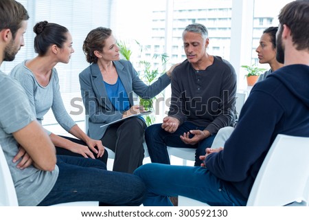 Concerned woman comforting another in rehab group at a therapy session