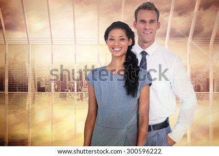 Happy business people smiling at camera against room with large window looking on city