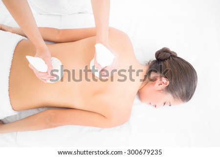 Beautiful brunette enjoying a herbal compress massage at the health spa