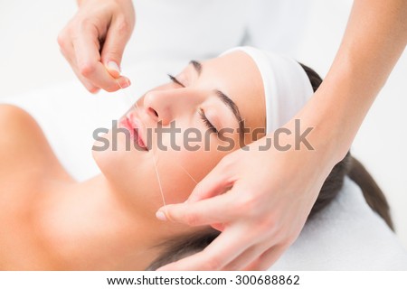 Close up of a hands threading beautiful womans upper lip