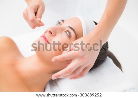 Close up of a hands threading beautiful womans upper lip