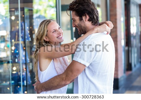 Smiling couple embracing and looking at each other at shopping mall