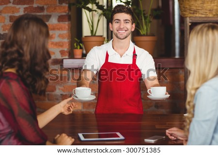 Portrait of a waiter serving coffees to customers at the coffee shop