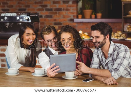 Smiling friends looking at digital tablet at the coffee shop