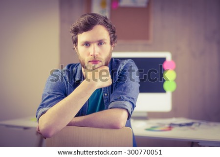 Bearded hipster frowning at camera in his office