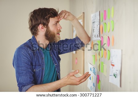 Bearded hipster looking at brainstorm wall in his office