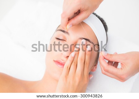 Close up of a hands threading beautiful womans upper eyes