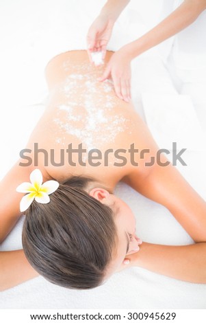 Beautiful brunette enjoying a salt scrub treatment at the health spa