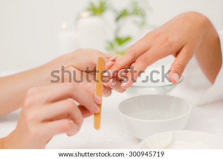 Close up of beautician filing female clients nails at spa beauty salon