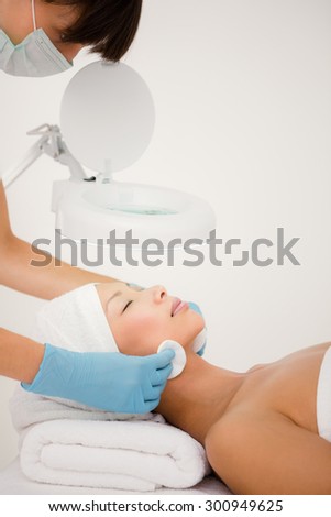 Side view of hands cleaning woman face with cotton swabs at spa center