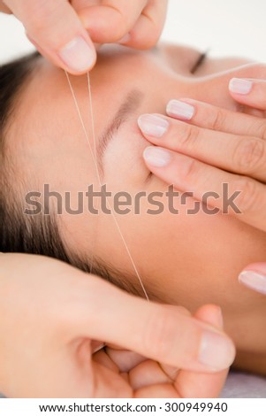 Close up view of hands threading beautiful womans eyebrow