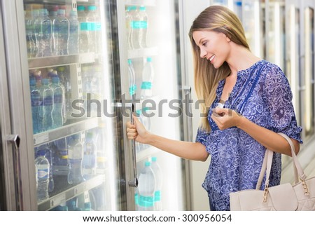 A pretty smiling blonde woman buying frozen products at supermarket