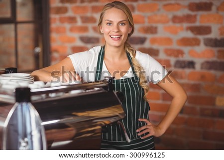 Portrait of a pretty barista with hands on hips at the coffee shop