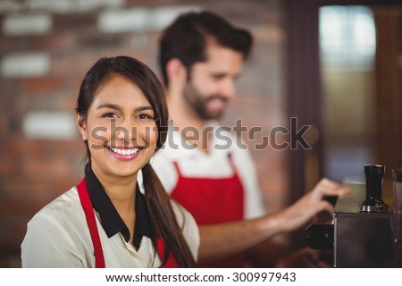 Portrait of a waitress using the coffee machine at the coffee shop