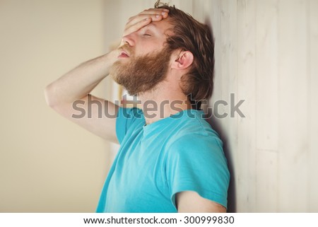 Troubled hipster leaning against wall in side view