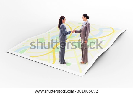 Two businesswomen shaking hands against city map
