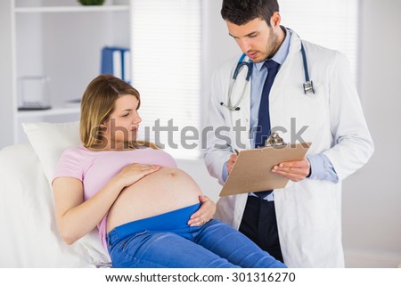 Doctor giving advice to lying pregnant patient in medical office