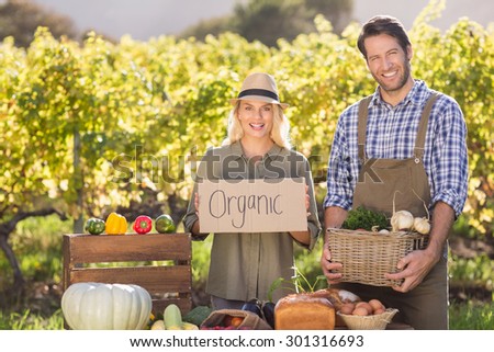 Portrait of a farmer couple holding a basket and organic sign