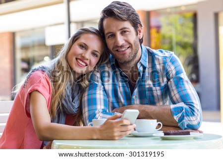 Smiling couple having tea in a cafe on a sunny day