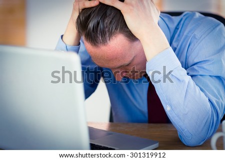Stressed businessman with head in hands at office