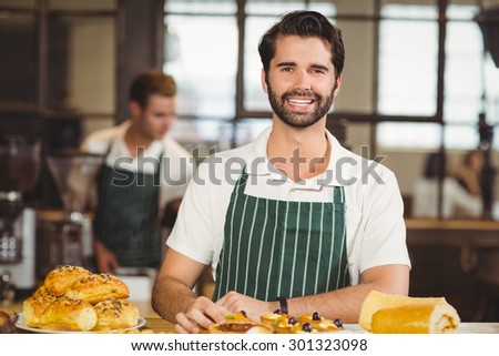 Portrait of a waiter tidying up the pastries at the coffee shop