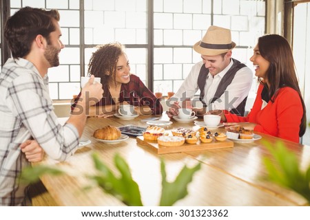 Laughing friends enjoying coffee and treats at coffee shop