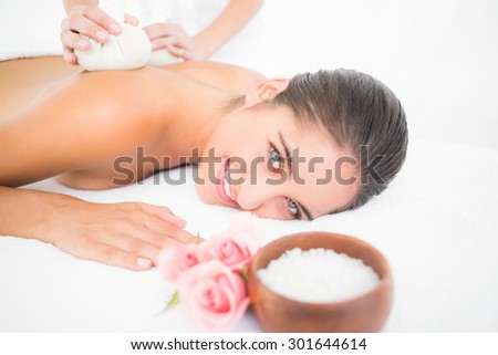 Portrait of a beautiful brunette enjoying a herbal compress massage at the health spa
