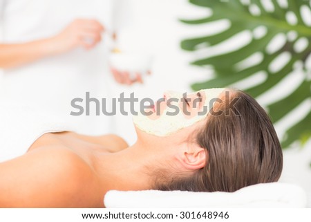 Side view of an attractive woman having white cream on her face at spa center