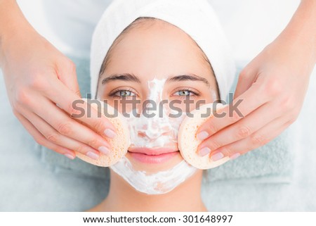 Upward view of hands cleaning woman face with cotton swabs at spa center