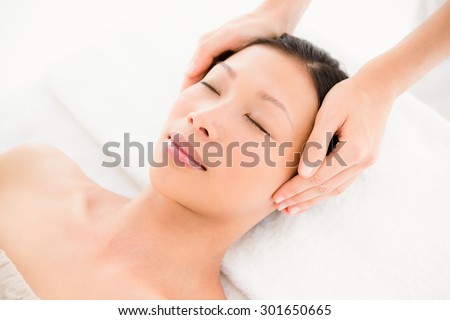 Side view of an attractive young woman receiving head massage at spa center