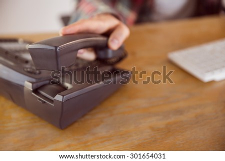 Hipster businessman answering the phone in his office