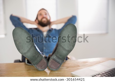 Hipster businessman relaxing at his desk in his office
