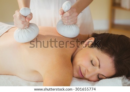 Young woman getting herbal compress massage in therapy room