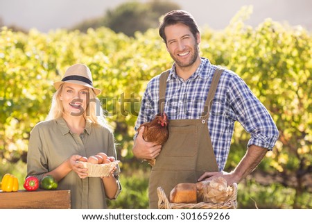 Portrait of a smiling farmer couple holding chicken and eggs